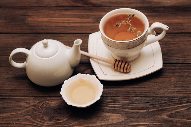 Miel de tilo fresca líquida en un plato con una cuchara de miel de madera y té