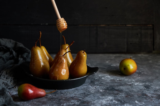 La miel vertió peras al horno en un plato