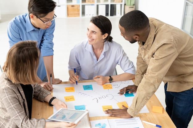 Foto los miembros del equipo del proyecto de inicio intercambian ideas creativas mientras hacen una lluvia de ideas sobre el proyecto en la reunión