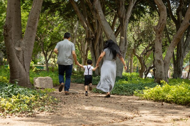 Miembros de la familia tomados de la mano y caminando hacia atrás en un parque juntos como familia