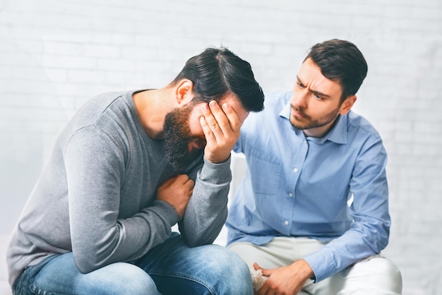 Miembros del grupo consolando a un hombre adicto que llora en una sesión de rehabilitación