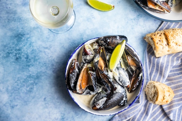 Miesmuscheln in Weinsauce, serviert mit Limette und Brot Muscheln in Weinlauch und Blauschimmelkäse geschmort