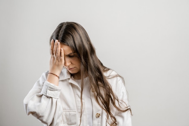 Migraña y dolores de cabeza en mujeres Chica morena con cabello largo sobre un fondo gris