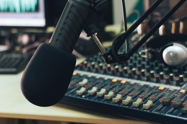 Mikrofon des Radiomoderators in Nahaufnahme mit dem Hintergrund der Mischpult-Tonsäule und Kopfhörer Radio Studio