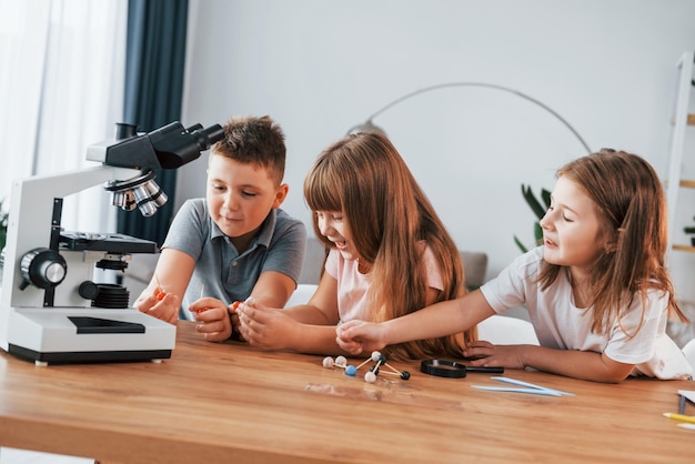 Mikroskop verwenden Kinder, die sich tagsüber gemeinsam im Wohnzimmer amüsieren