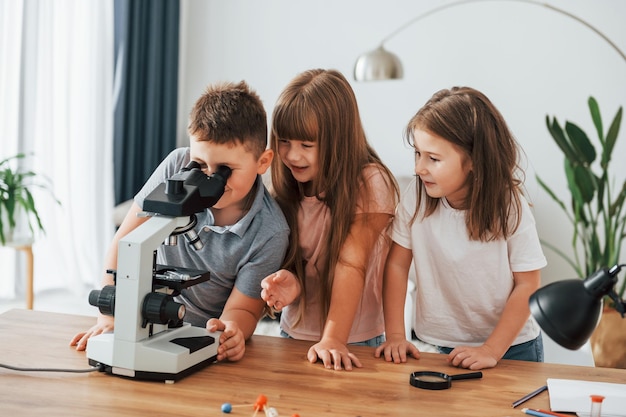 Mikroskop verwenden Kinder, die sich tagsüber gemeinsam im Wohnzimmer amüsieren