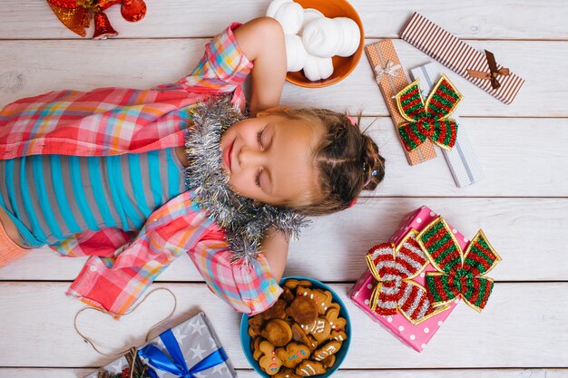 Milagre de Natal da vida dos sonhos para criança Garota alegre da época favorita do ano com doces saborosos em fundo de madeira Yummy apresenta o conceito de felicidade