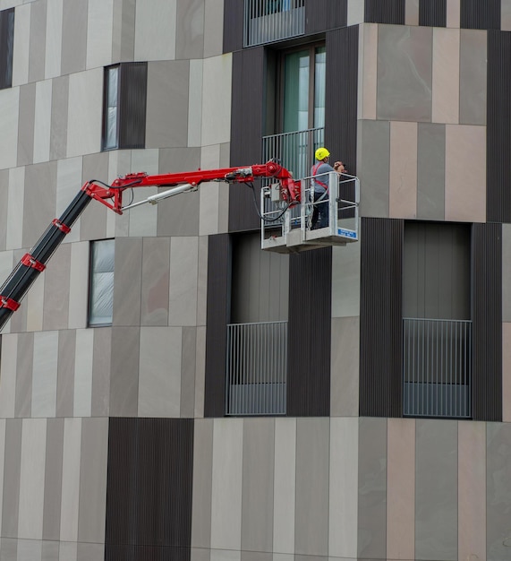 Milán italia 8 de septiembre de 2020 trabajador de la construcción en un elevador de pluma en el costado de un edificio