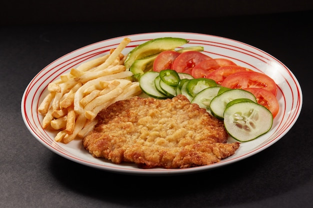 Milanesa de pollo com papas fritas y ensalada de pepino tomate y aguacate