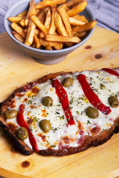 Milanesa a la napolitana y bol con papas fritas