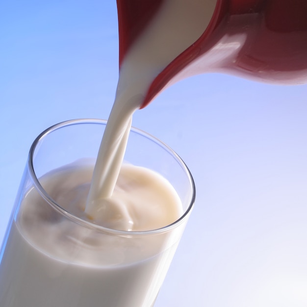 Foto milch aus einem roten krug in glas gegossen