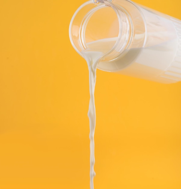 Foto milch, die aus dem decanter ello hintergrund fließt