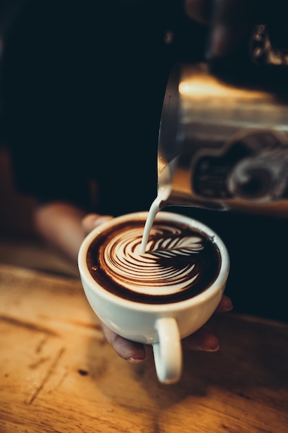 Milch, die in einer Kaffeetasse auf den Tisch gegossen wird