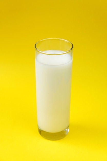 Milch im Glas auf gelbem Hintergrund isoliert