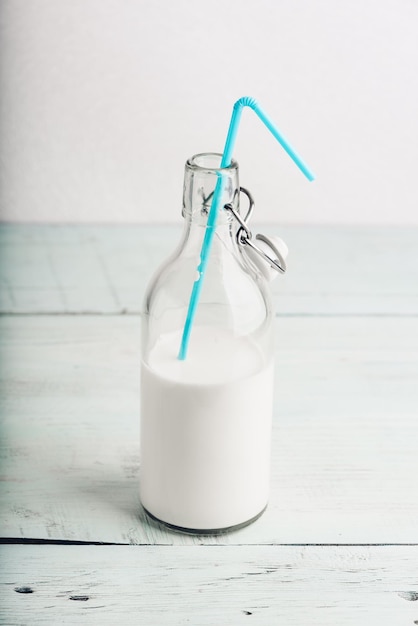 Milch in der Flasche mit blauem Stroh