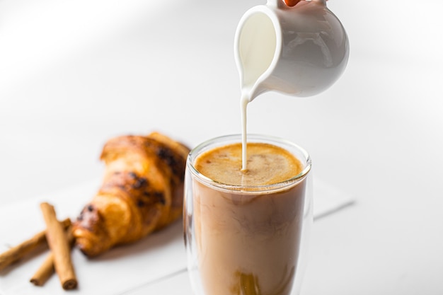 Milch in ein Glas Kaffee Latte gießen