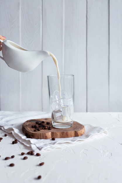 Milch in ein Glas mit Eis gießen