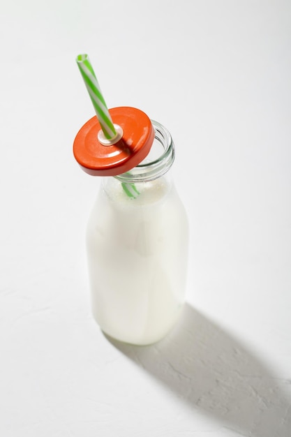 Milch in einer Flasche mit einem Strohhalm auf weißem Hintergrund Pflanzliche Milch oder Joghurt