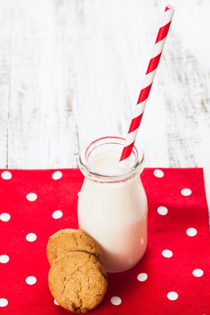 Milch in Flasche mit Papierstroh mit Keksen