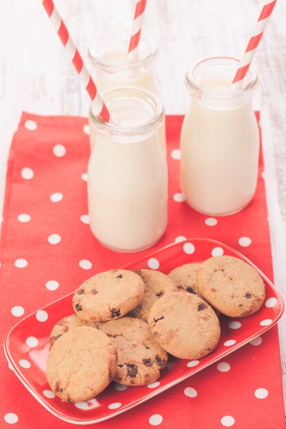 Milch in Flasche mit Papierstroh mit Keksen