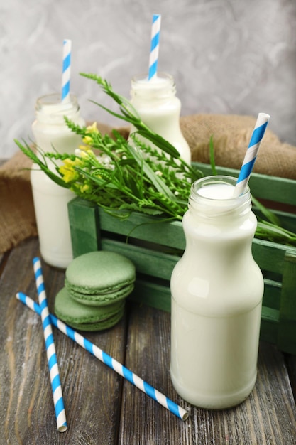 Milch in Flaschen mit Papierstrohhalmen auf dem Tisch