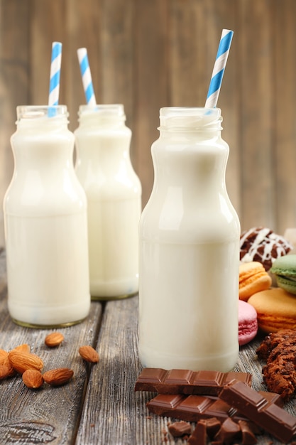 Milch in Flaschen mit Papierstrohhalmen auf dem Tisch