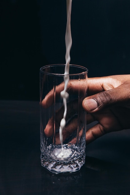 Milch in Glas in der Hand des schwarzen Mannes gießen, Nahaufnahme