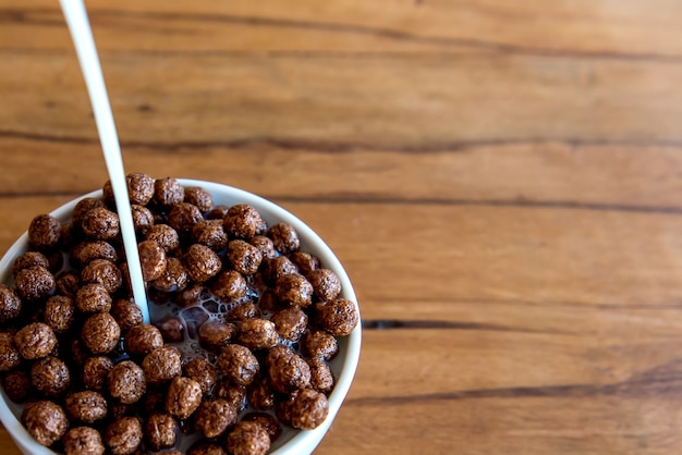 Milch in Schokoladen-Cornflakes-Kugeln gießen Frühstück mit Milch und Cornflakes.