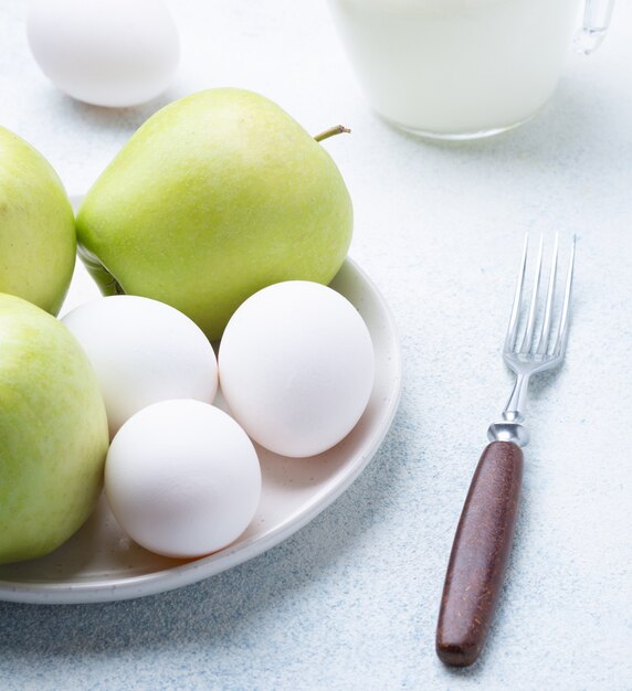 Milch, Mehl, Eier und grüne Äpfel auf einem weißen Hintergrund. Zutaten für Apfel Charlotte. Rezept