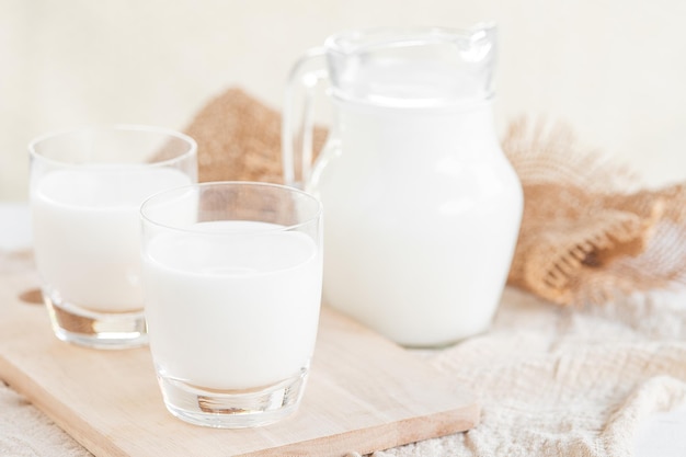 Milch. Milchflasche und Milchglas auf Holztisch. Glaskrug und Glas mit Milch. Konzept der gesunden Ernährung