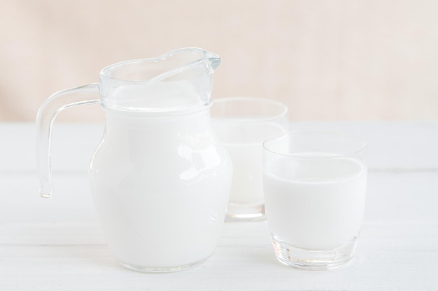 Milch. Milchflasche und Milchglas auf Holztisch. Glaskrug und Glas mit Milch. Konzept der gesunden Ernährung