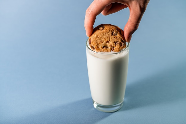 Milch mit Spritzer und Kekse des Schokoladengeschmacks auf blauem Hintergrund.