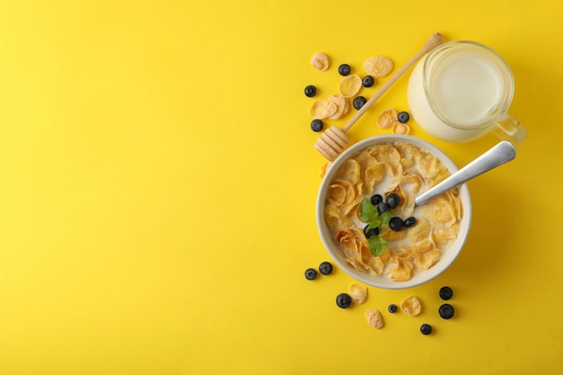 Milch, Müslischale und Löffel auf Gelb