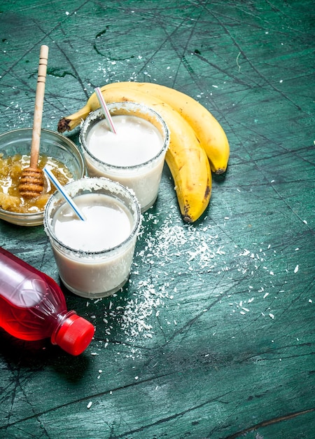 Milch-Smoothie mit Banane, Erdbeersirup und Honig. Auf rustikalem Hintergrund.