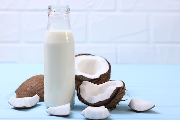 Milch und gebrochene Kokosnüsse auf dem Tisch Pflanzenmilch ein Veggie-Drink