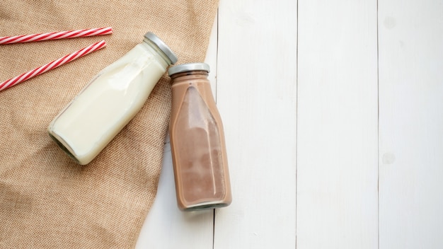 Milch- und Schokoladenmilch auf einem weißen Holztisch.