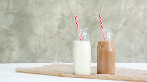 Milch- und Schokoladenmilch auf einem weißen Holztisch.