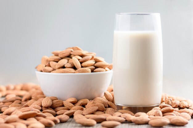 Milch und Stapel der Mandelnuss in einer Weile rollen gegen hölzernen Hintergrund