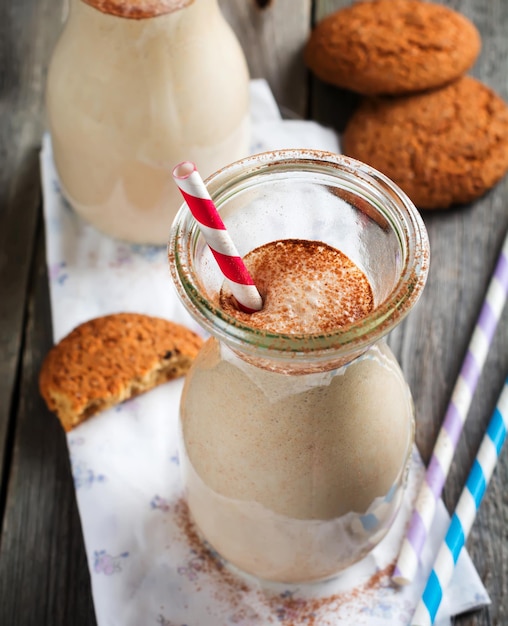 Milch-Vanille-Smoothies mit Haferkeksen in Glasgefäßen auf dem alten Holzhintergrund. Selektiver Fokus.