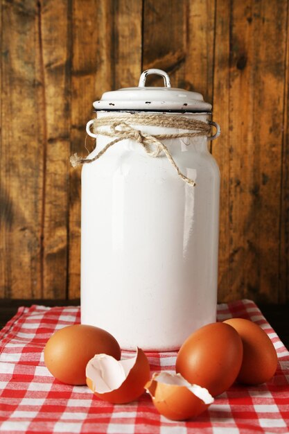 Foto milchdose mit eiern und eierschalen auf serviette auf rustikalem holzhintergrund