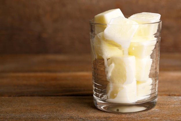 Milcheiswürfel im Glas auf Holzhintergrund