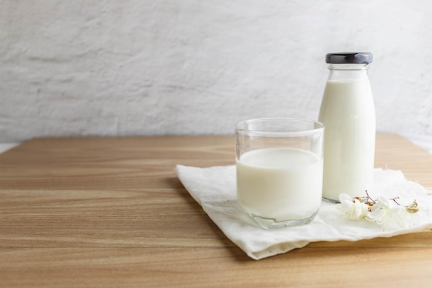 Milchflasche und Glas Milch auf Holztisch