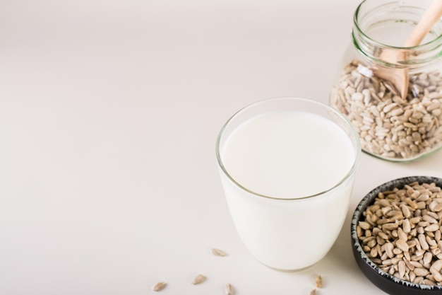 Milchfreie Sonnenblumenmilch in einem Glas und Samen in einer Schüssel auf dem Tisch Gesunde Ernährung