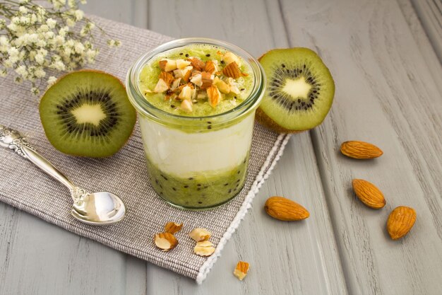 Milchjoghurt mit Kiwi und Nüssen auf dem grauen Holz