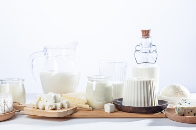 Milchprodukte in Glasempfängern und Holzschalen auf weißem Hintergrund.