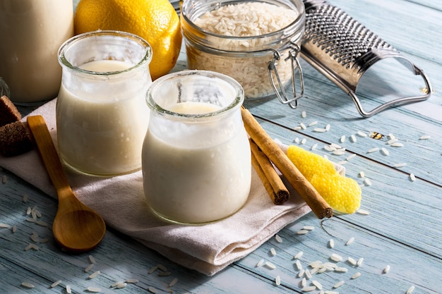 Milchreis in Gläsern mit Zimtstangen auf hellblauem Holztisch