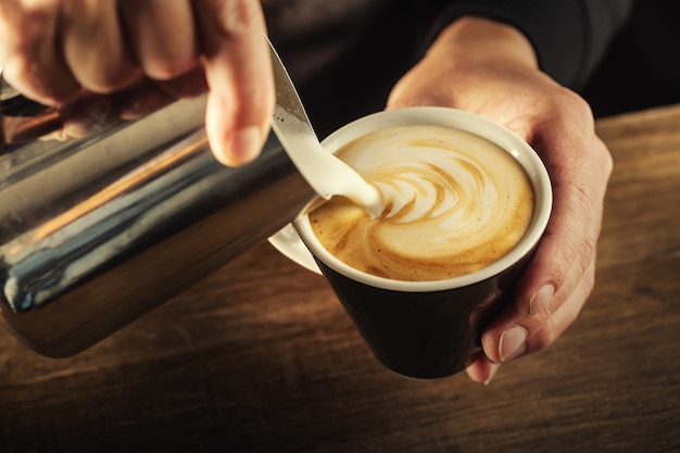 Milchschaum in eine Tasse zu einem perfekten Cappuccino gegossen - Kaffeekunst.
