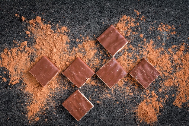 Milchschokoladenriegel-Schokoladenstückchen und Kakao auf Schwarz