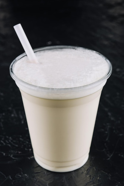 Milchshake in einem Plastikbecher auf schwarzem Hintergrund