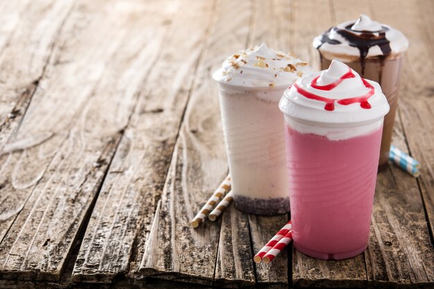 Milchshakes mit Erdbeeren, Schokolade und weißem Eis auf dem Kopierraum des Holztischs